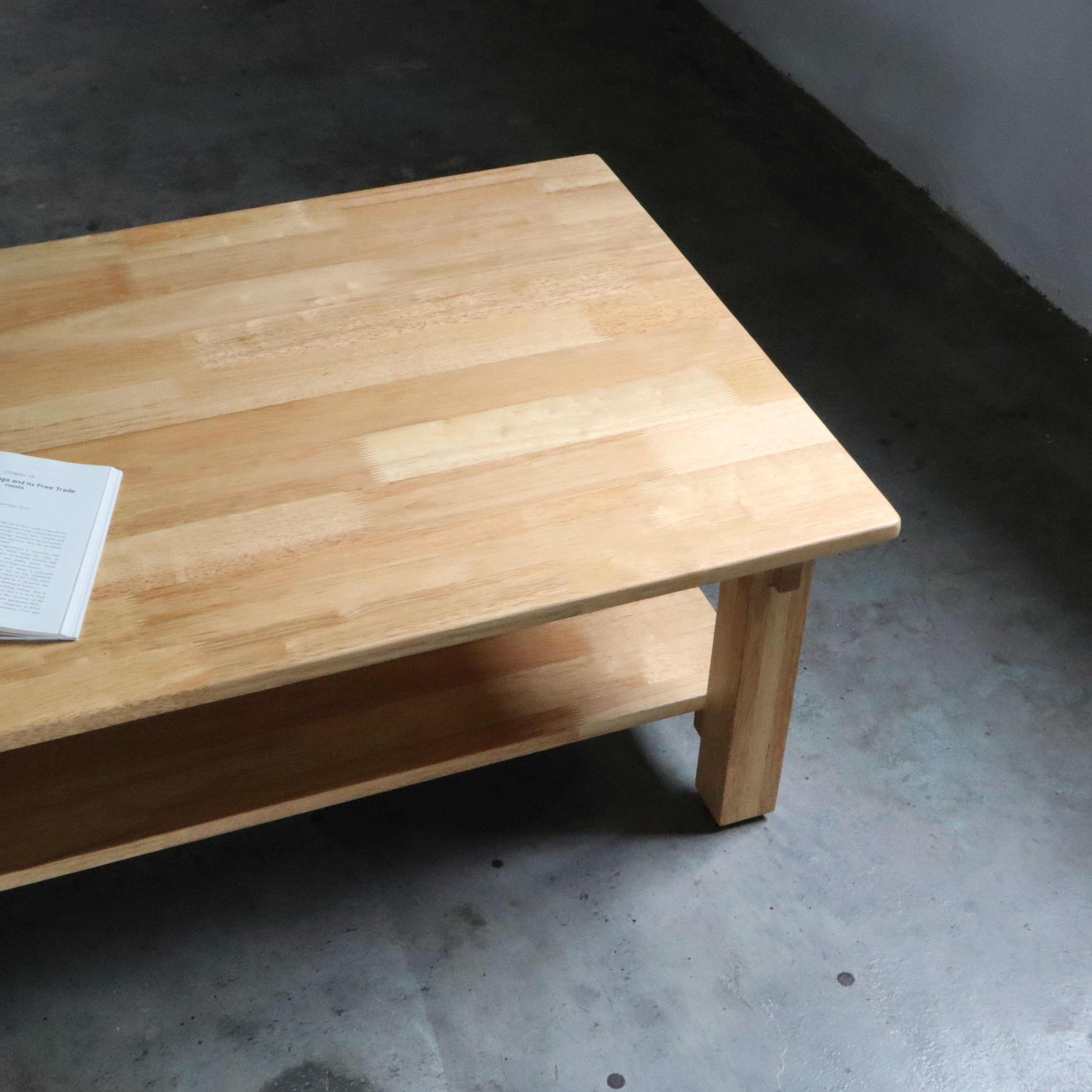 Wooden coffee table with a newspaper on a concrete floor