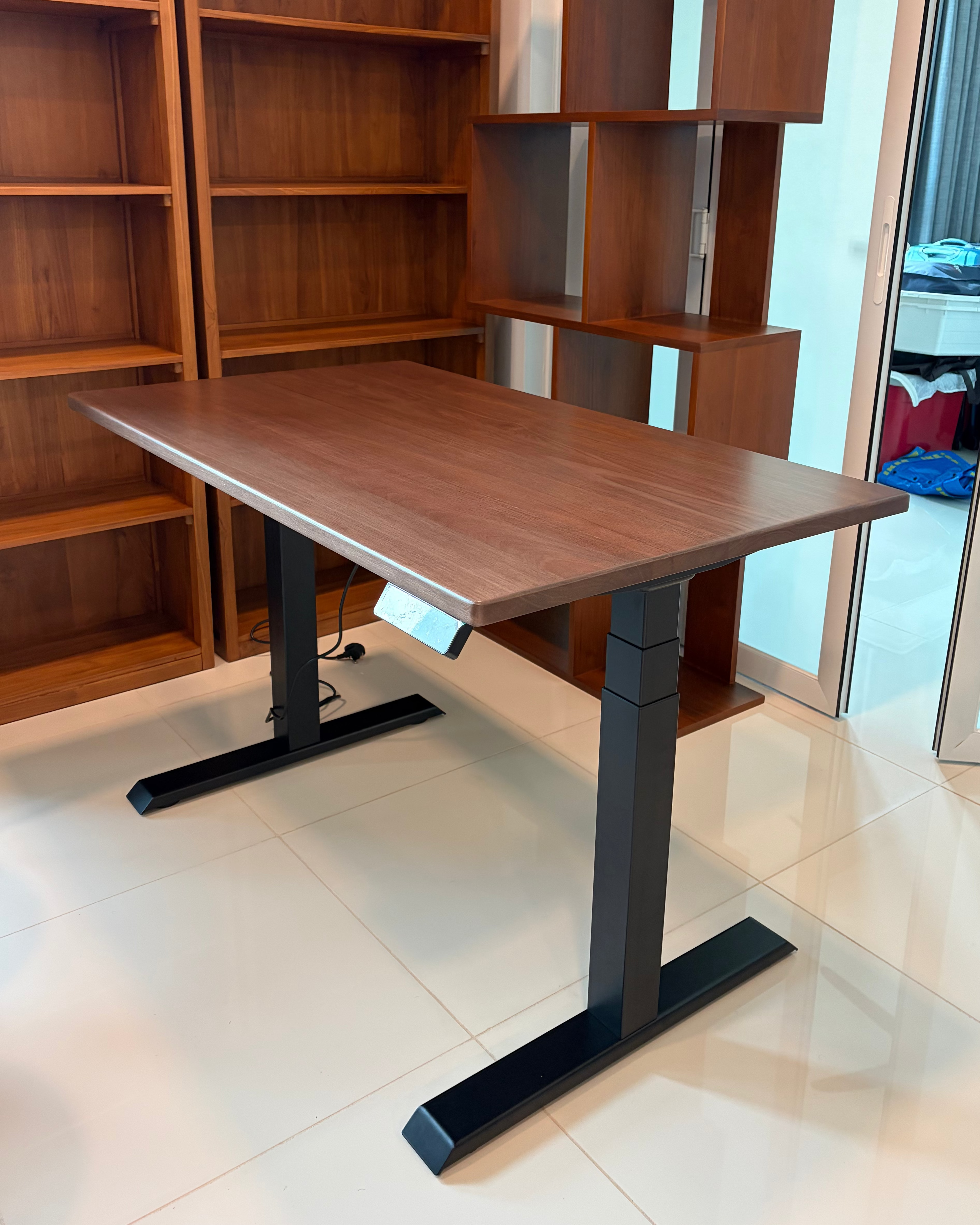 Wooden desk with adjustable height in a room with bookshelves and a mirror.