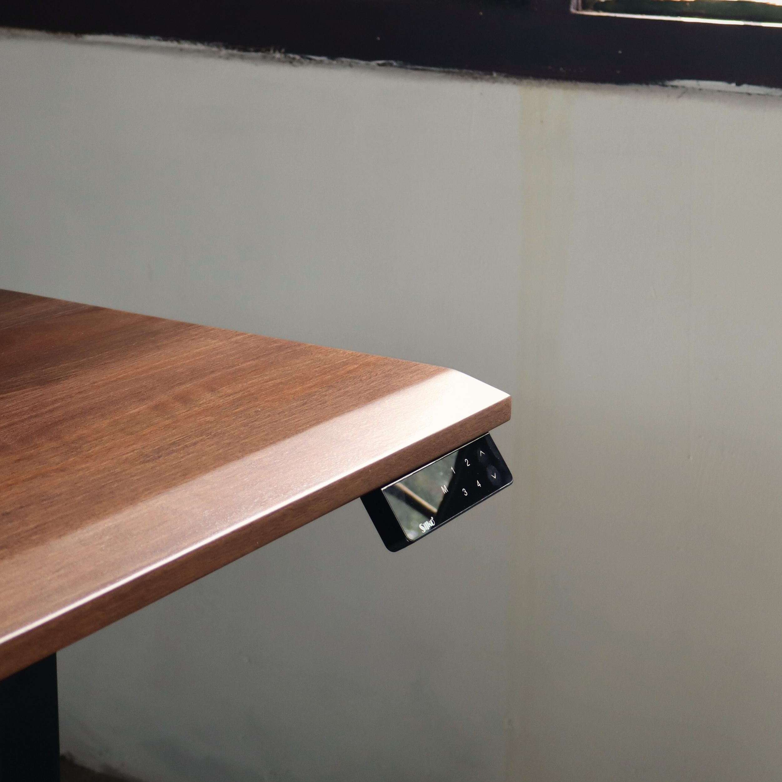 Wooden standing desk with a control panel on a gray wall background