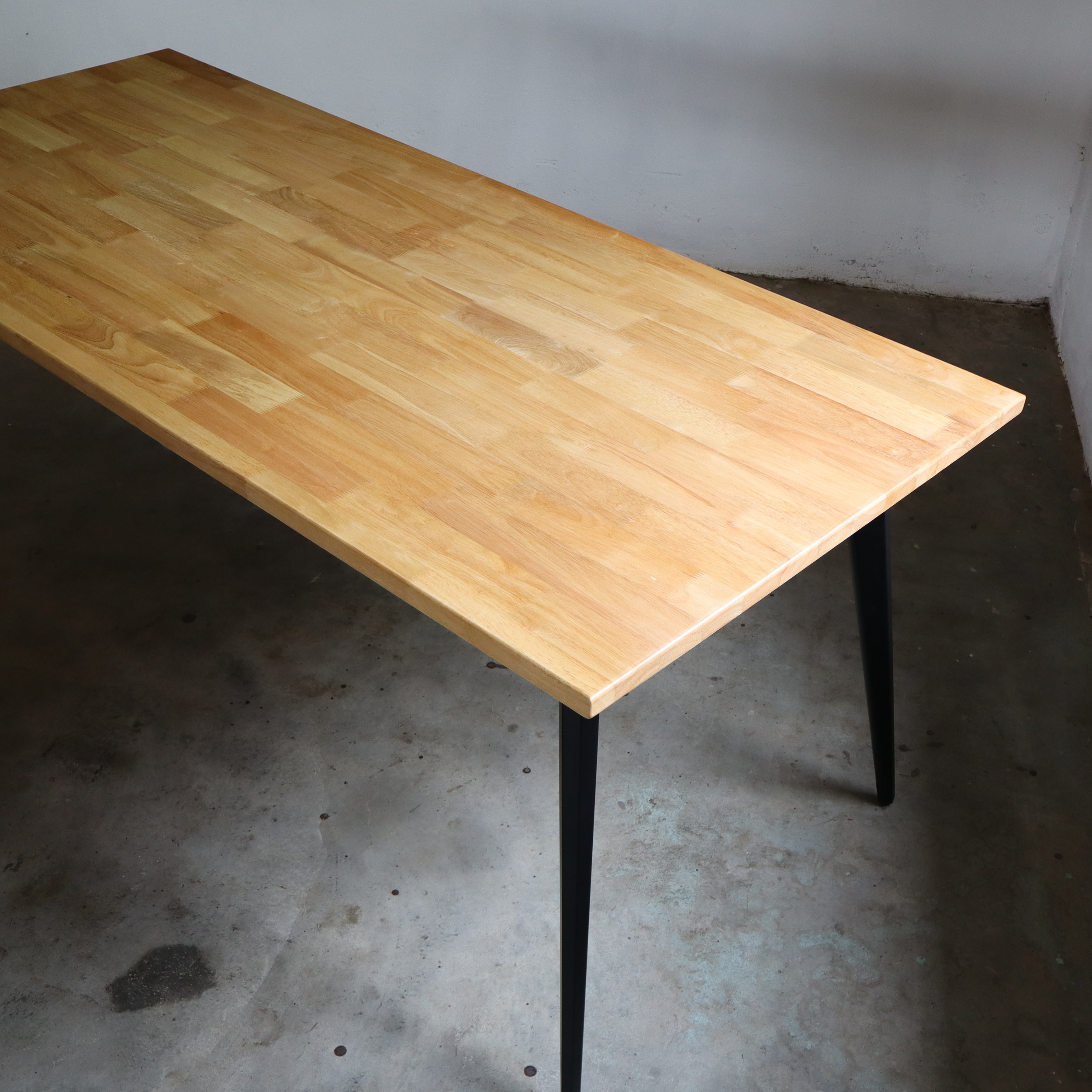 Wooden table with black legs on a concrete floor