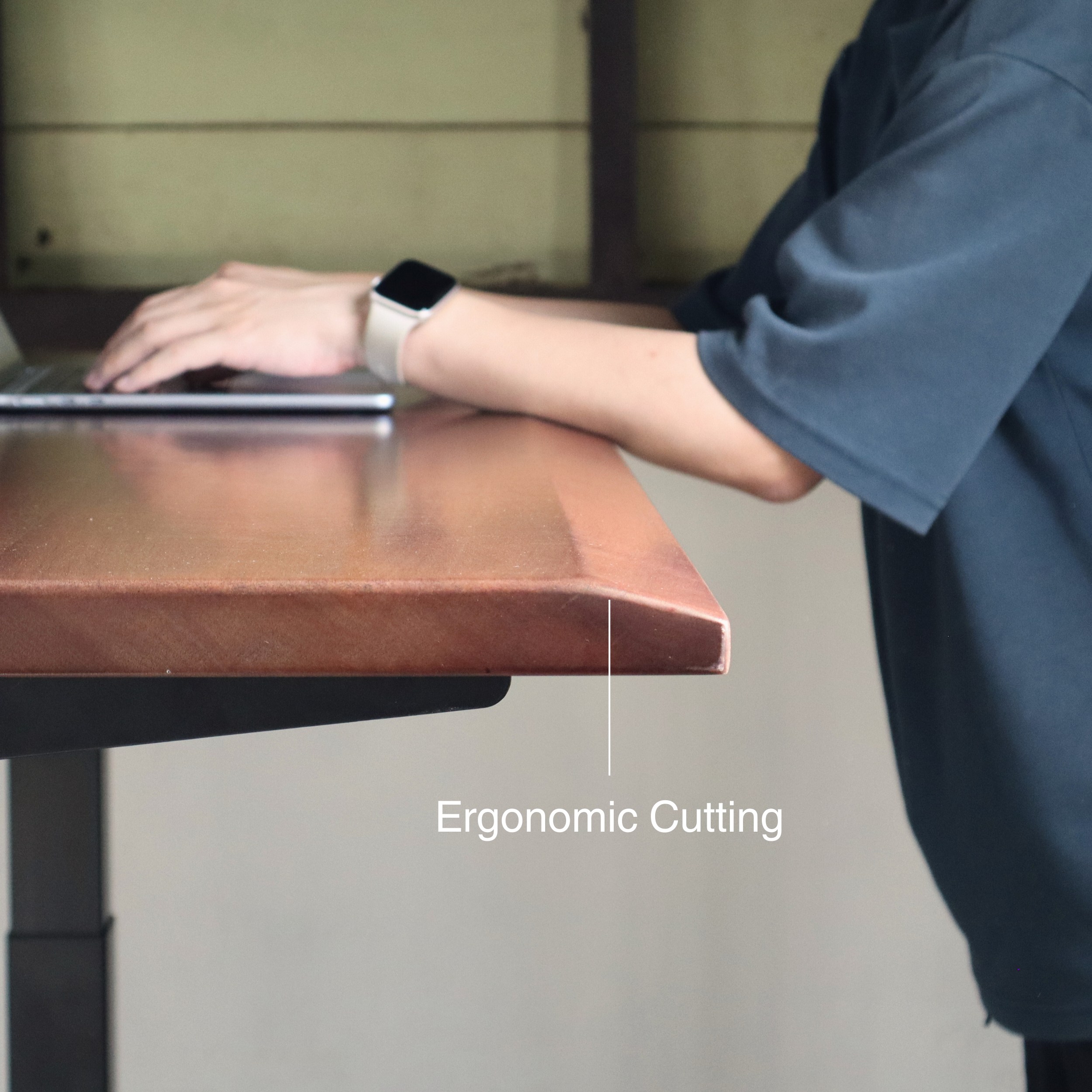 Person using a laptop on an adjustable desk with ergonomic cutting feature highlighted.