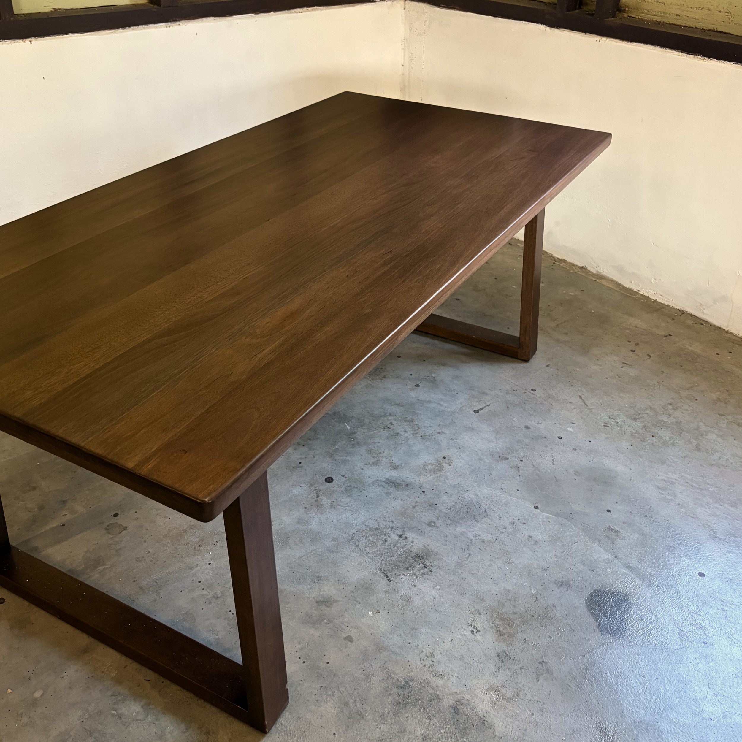 Wooden table with a dark finish on a concrete floor.