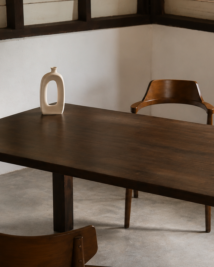 Wooden dining table with chairs in a room with mirrors on the wall.
