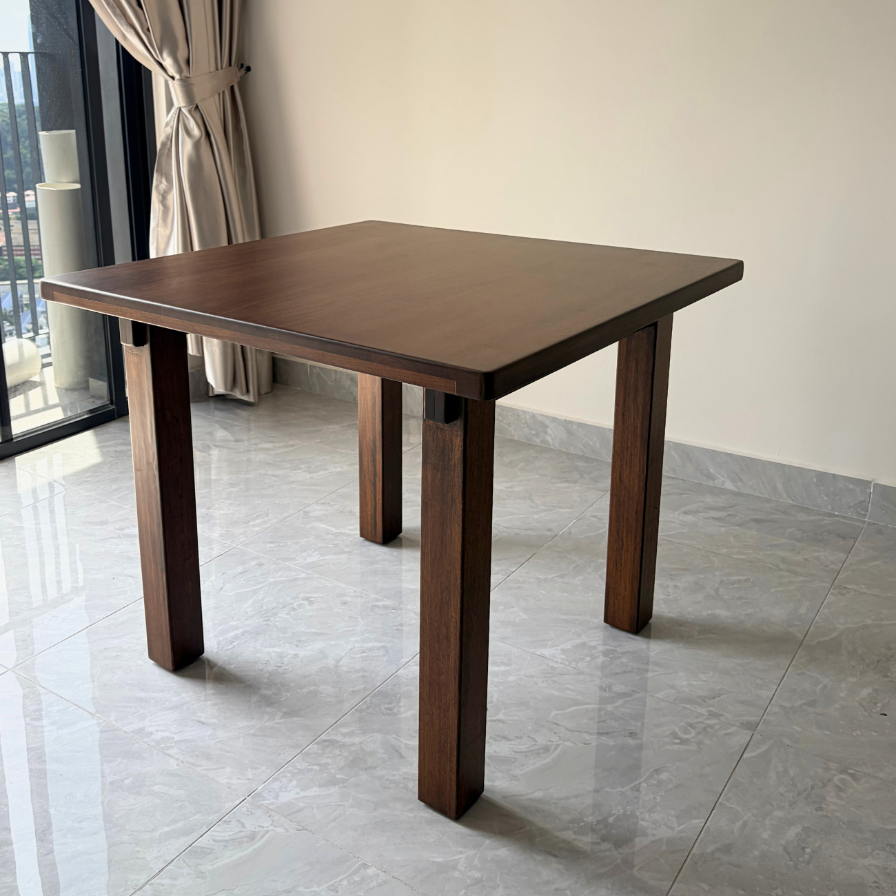 Wooden table in a room with a curtain and tiled floor