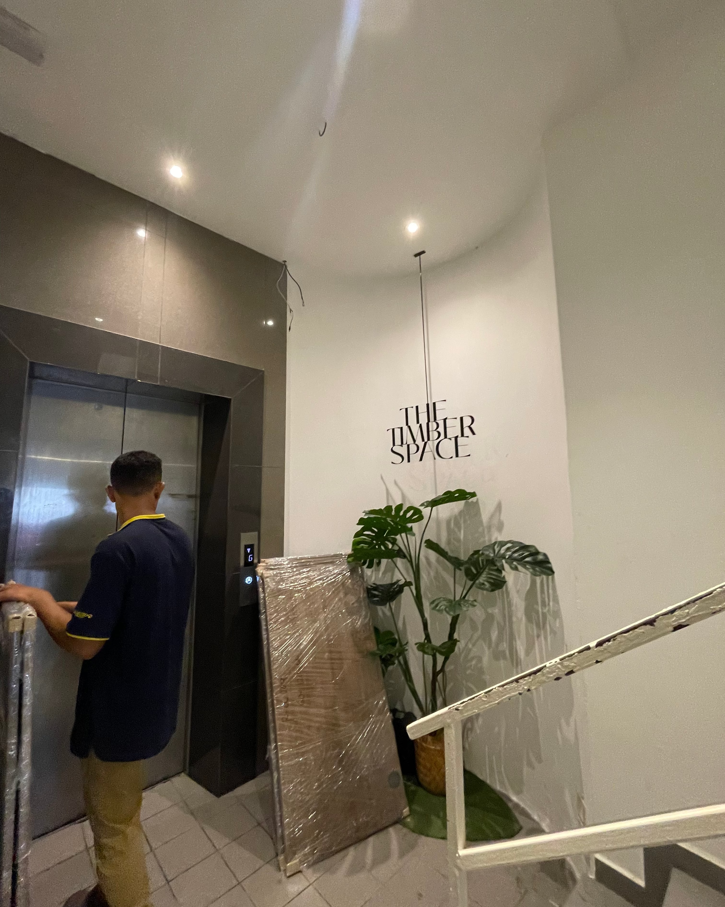Person using an elevator in a modern building with 'The Hub Space' branding.